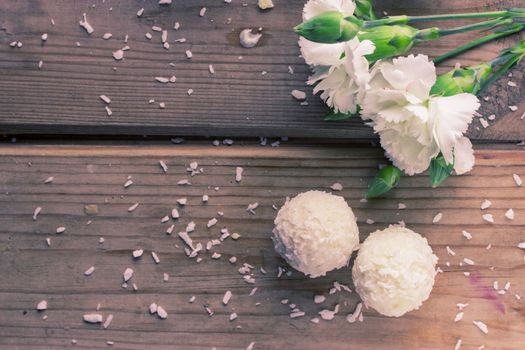 White sweet coconut truffles and flowers, close up