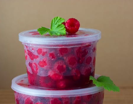 Raspberry in the round box with leaf of mint on the old wood background