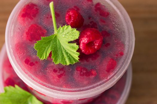 Raspberry in the round box with leaf of mint on the old wood background