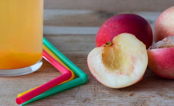 Ripe peaches and glass of juice on wooden background