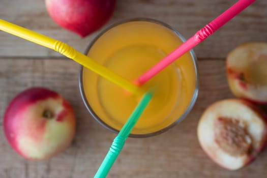 Ripe peaches and glass of juice on wooden background