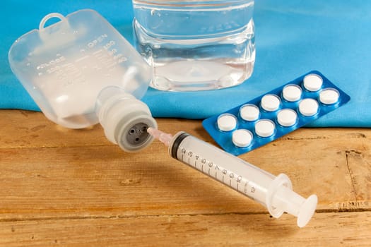 drug and saline solution and injection needle on wood table