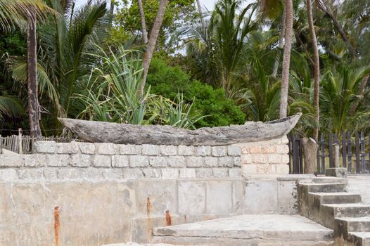 Old wooden canoe posing on a low wall separating Bamburi beach in Kenya from holiday makers