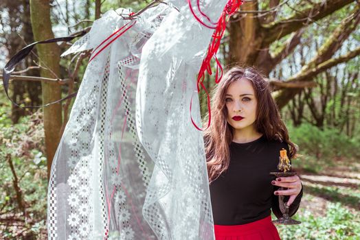 mysterious woman witch in the woods with a candle hidden behind the curtains