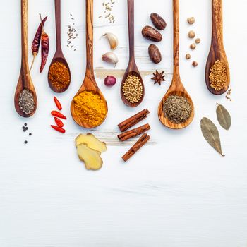 Various of Indian spices and herbs in wooden spoons. Flat lay of spices ingredients chili ,paprika ,peppercorn, dried thyme, cinnamon,star anise and curry powder on the shabby wooden.