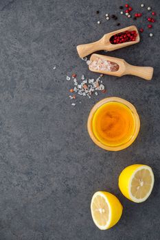 The lemon vinaigrette dressing ingredients lemon, olive oil, himalayan salt and pepper corn on dark stone background with flat lay and copy space.