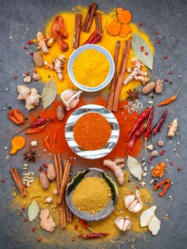 Various of spices and herbs in ceramic bowl. Flat lay of spices ingredients chilli ,pepper corn, garlic, oregano, cinnamon, star anise, nutmeg, mace, ginger and bay leaves on dark stone background.