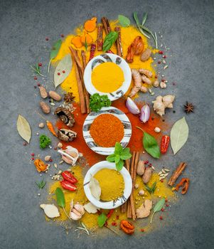 Various of spices and herbs in ceramic bowl. Flat lay of spices ingredients chilli ,pepper corn, garlic, oregano, cinnamon, star anise, nutmeg, mace, ginger and bay leaves on dark stone background.