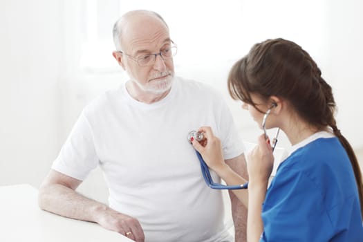 Doctor examining heartbeat of senior male patient