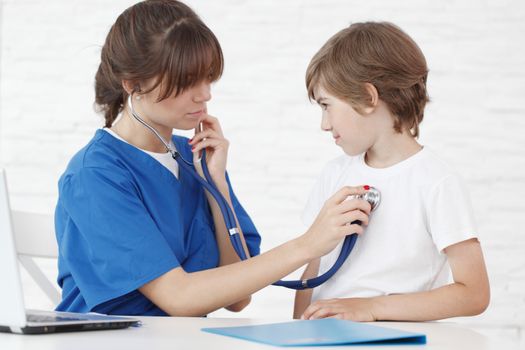 Female doctor listening to heartbeat of a boy, isolated on white