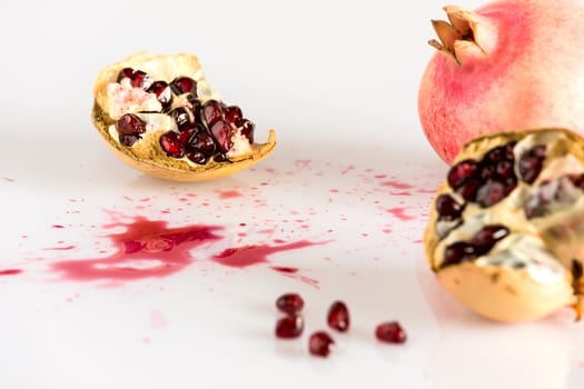 Half pomegranate and seeds on white background