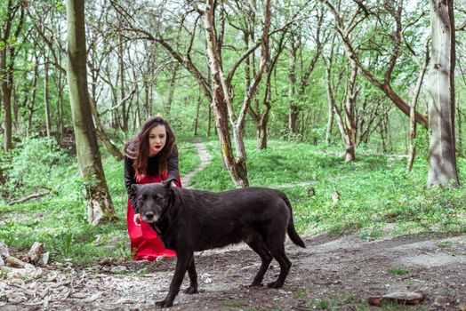 mysterious woman witch with a black dog in the spring forest