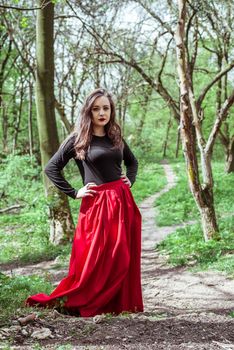 beautiful woman in a red dress standing in the spring forest