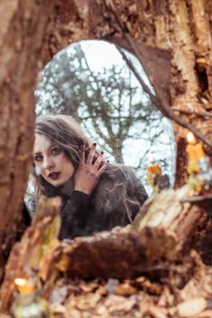 mystical woman looks in the mirror near a tree at the spring forest