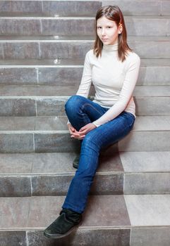 teen girl sitting on stairs. Indoor portrait of a sad teenage girl 