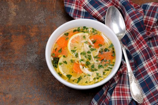 Homemade, tender soup with chicken, lemon, orzo, and fresh parsley leaves