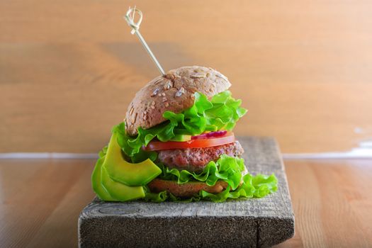 Delicious homemade burger on rustic wooden desk 