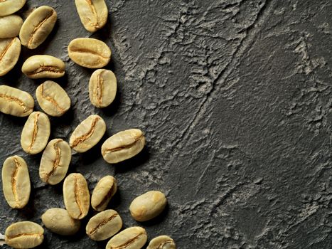 Green coffee beans on dark concrete background. Top view or flat lay. Copy space. Image with natural colors