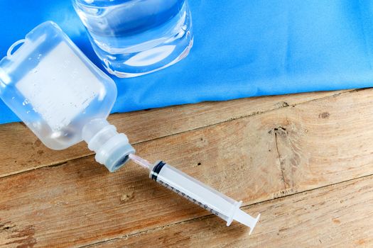 saline solution and injection needle on wood table