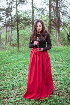 mystical witch woman in a red skirt with a candle in spring forest