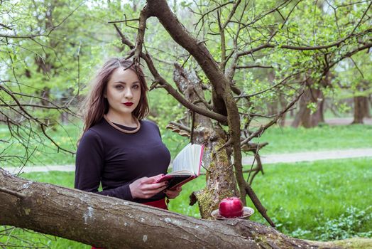 woman reading a book near a tree in the spring forest