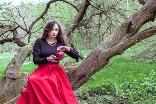 girl in a red skirt sitting on a tree trunk with apple in hand