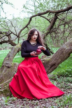 girl in a red skirt sitting on a tree trunk with apple in hand