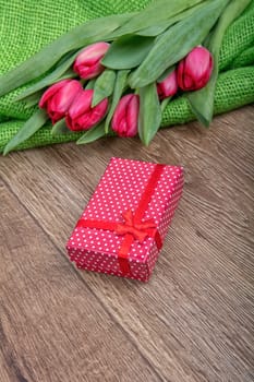 Red tulips and red gift on a wooden background