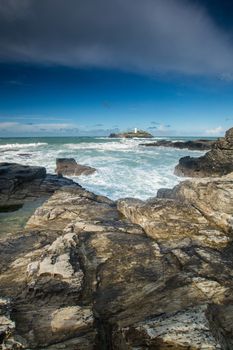 The lighthouse at Gwithian, in West Cornwall with rocks in the foreground