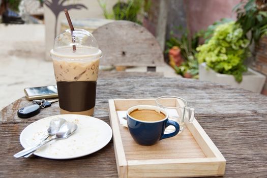 empty cake on white plate and empty hot espresso and ice coffee on old wood table