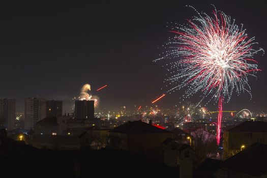 Colorful fireworks celebration and the city night light background.