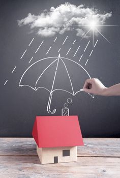 Umbrella being sketched on a chalkboard protecting a house