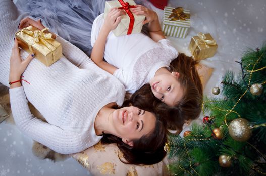 Mother and daughter lying under Christmas tree, upper view
