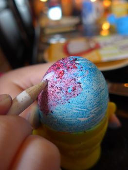kid drawing on an Easter egg