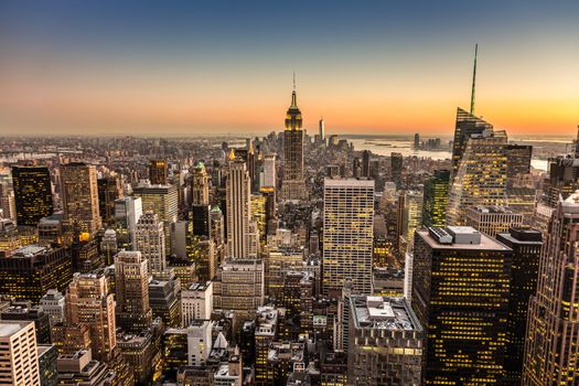 New York City. Manhattan downtown skyline with illuminated Empire State Building and skyscrapers at dusk.