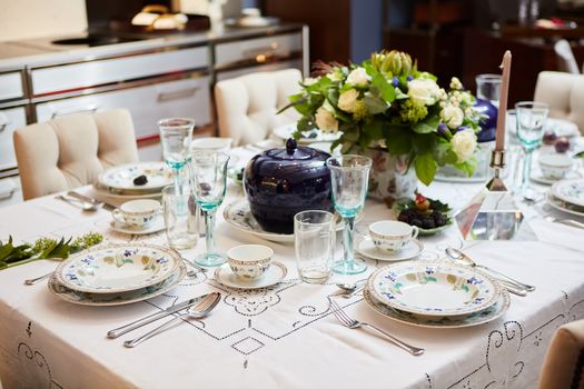 Decorated table ready for dinner. Beautifully decorated table set with flowers, candles, plates and serviettes for wedding or another event in the restaurant.