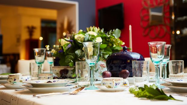 Decorated table ready for dinner. Beautifully decorated table set with flowers, candles, plates and serviettes for wedding or another event in the restaurant.