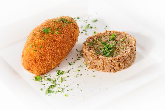 Big cutlet of turkey meat with garnish made of buckwheat cereal