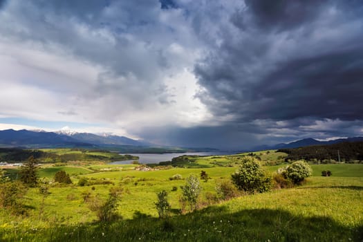 Spring rain and storm in mountains. Green spring hills of Slovakia. Spring stormy scene. Clouds and sunny countryside.