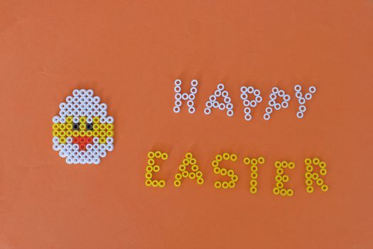 beaded chicken on an orange background with "HAPPY EASTER" made out of beads