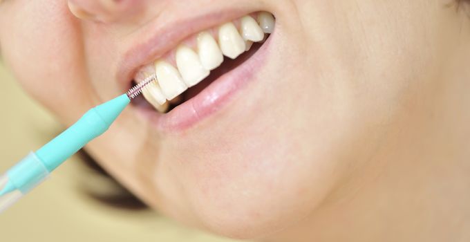 woman cleaning her teeth with an interdental brush