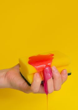 Hand with sponge with foam on yellow background