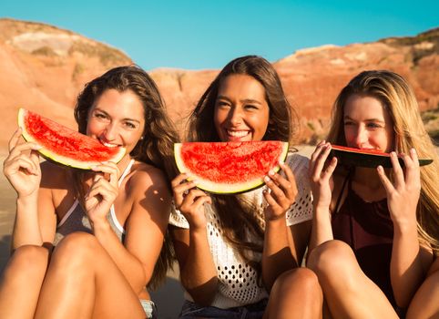 Best friends having fun on the beach and eating watermelon