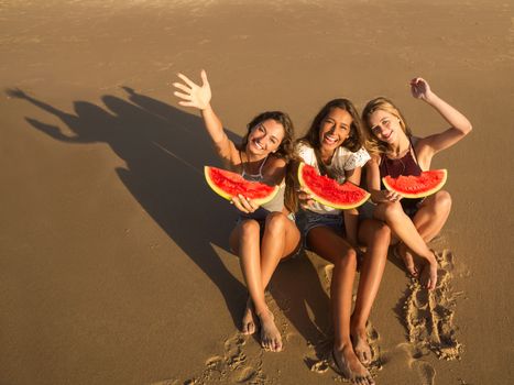 Best friends having fun on the beach and eating watermelon