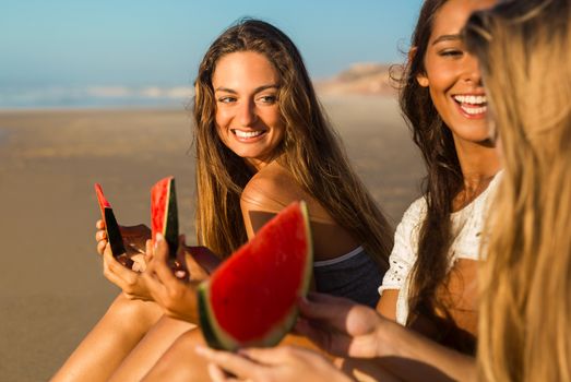 Best friends having fun on the beach and eating watermelon