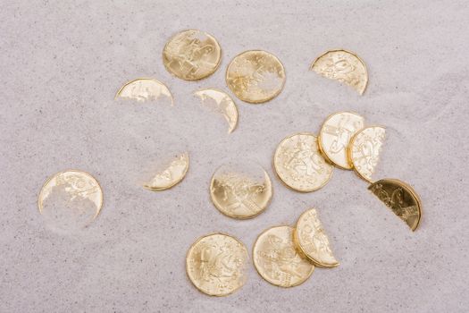 Gold coins on a grey sand background