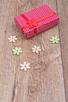 Gift with wooden flowers on a wooden background