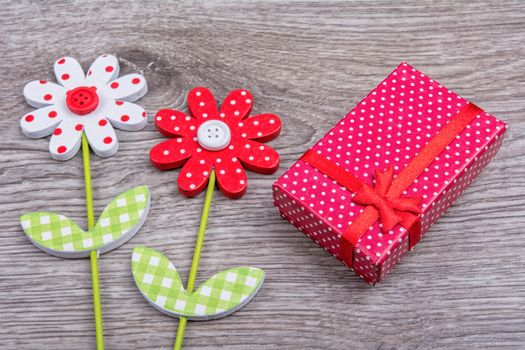 Wooden flowers with red gift on wooden background