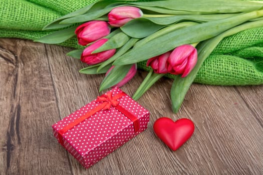 Red tulips, heart and red gift on a wooden background