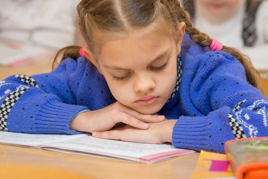 First grader to read the lesson reads the text in the book with his head in his hands